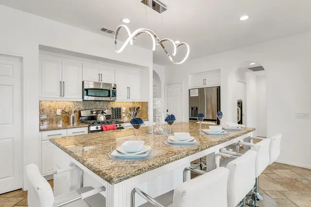 a kitchen with kitchen island granite countertop stainless steel appliances a sink a stove and cabinets