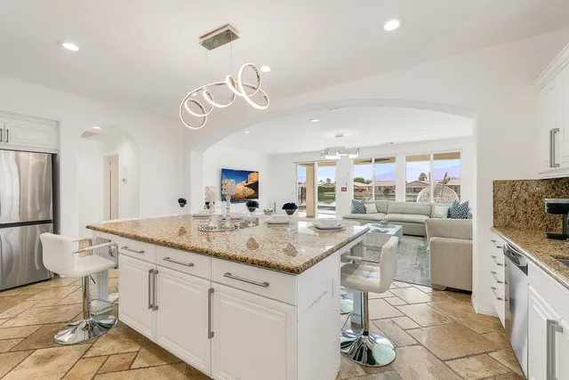 a kitchen with stainless steel appliances granite countertop a sink and a refrigerator