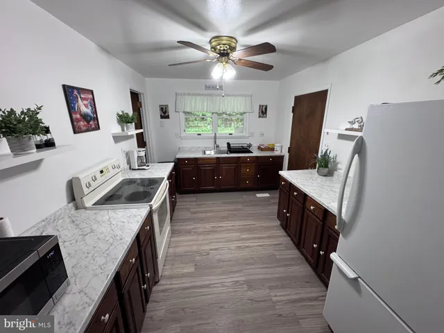 a large kitchen with granite countertop a refrigerator a sink dishwasher a dining table and chairs with wooden floor