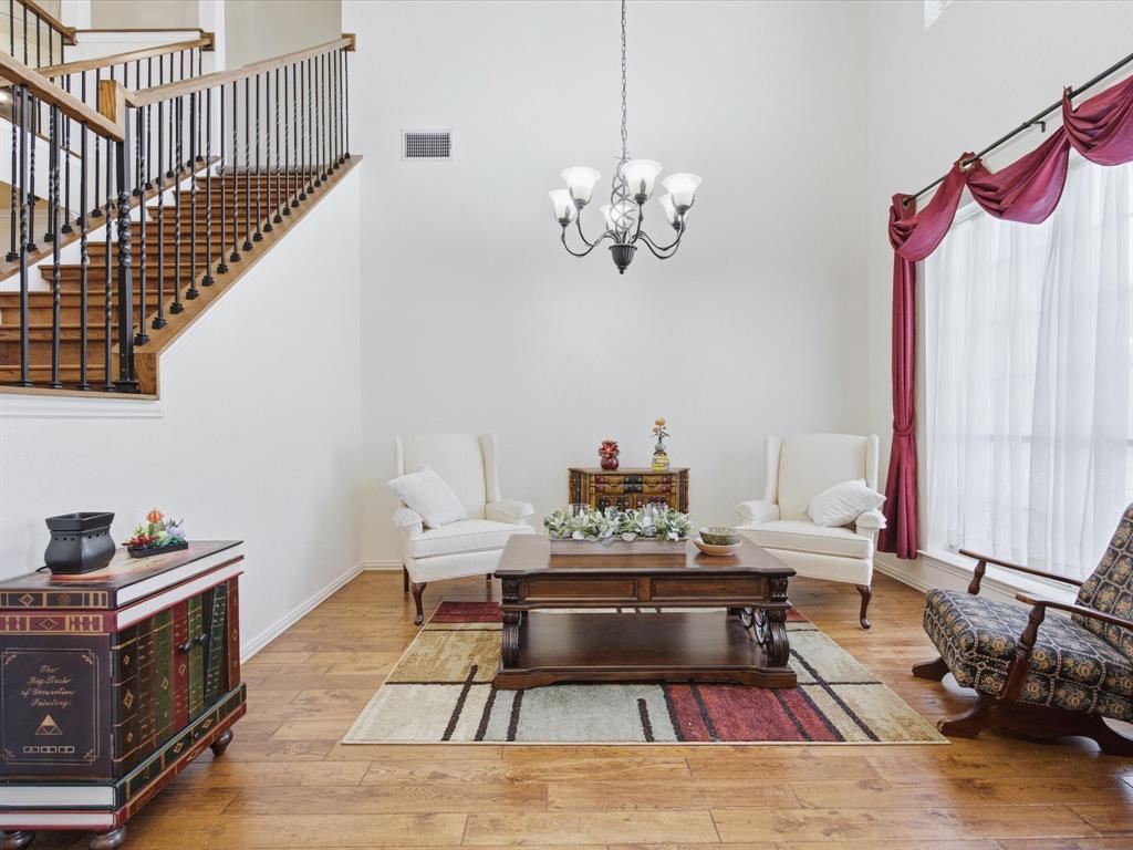 4008 Falcon Ridge Drive Haltom City, TX 76137 - Photo 5 of 40 Two-story foyer featuring high ceilings, a wrought iron chandelier, wood-finish flooring, and a staircase with an open railing