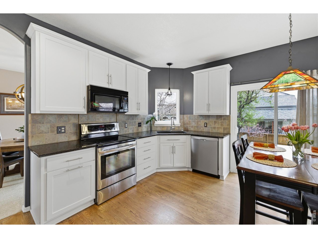 9734 Red Oakes Drive Highlands Ranch, CO 80126 - Photo 15 of 40 a kitchen with stainless steel appliances a stove a sink a microwave a dining table and chairs