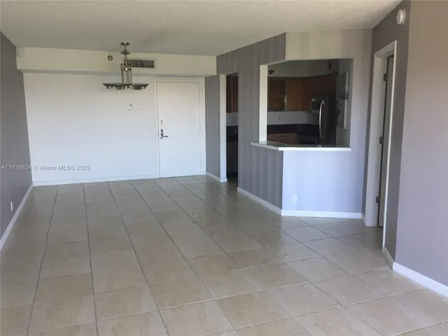 an empty room with an entryway and chandelier