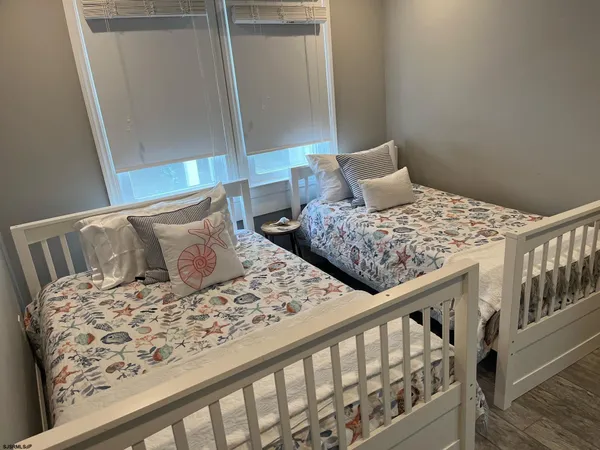 a bedroom with two beds and wooden floor