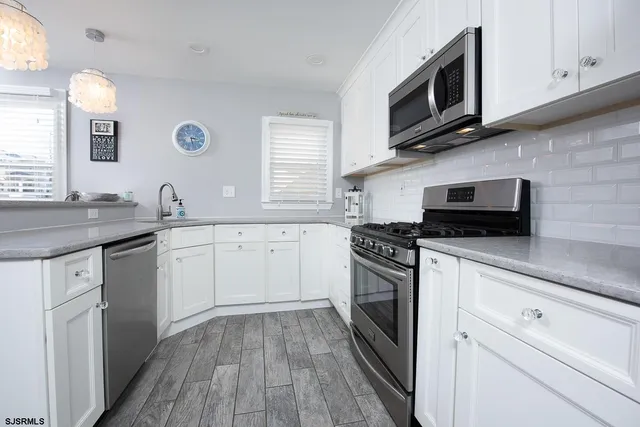 a kitchen with stainless steel appliances granite countertop a sink dishwasher a stove and a microwave oven with cabinets