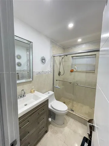 a bathroom with a shower sink mirror and toilet