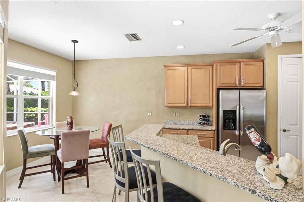 3951 Ruxton Road Naples, FL 34116 - Photo 19 of 35 a kitchen with granite countertop a dining table chairs refrigerator and sink