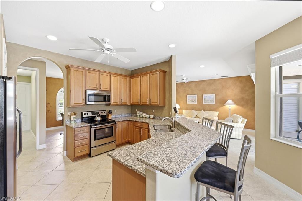 3951 Ruxton Road Naples, FL 34116 - Photo 20 of 35 a kitchen with granite countertop a stove refrigerator and microwave