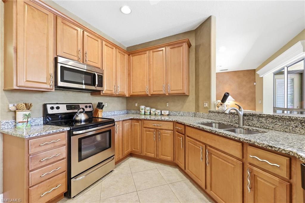 3951 Ruxton Road Naples, FL 34116 - Photo 21 of 35 a kitchen with stainless steel appliances granite countertop a stove sink microwave and cabinets