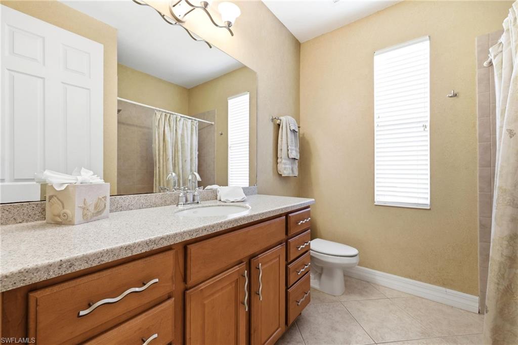 3951 Ruxton Road Naples, FL 34116 - Photo 27 of 35 a bathroom with a granite countertop sink toilet and mirror
