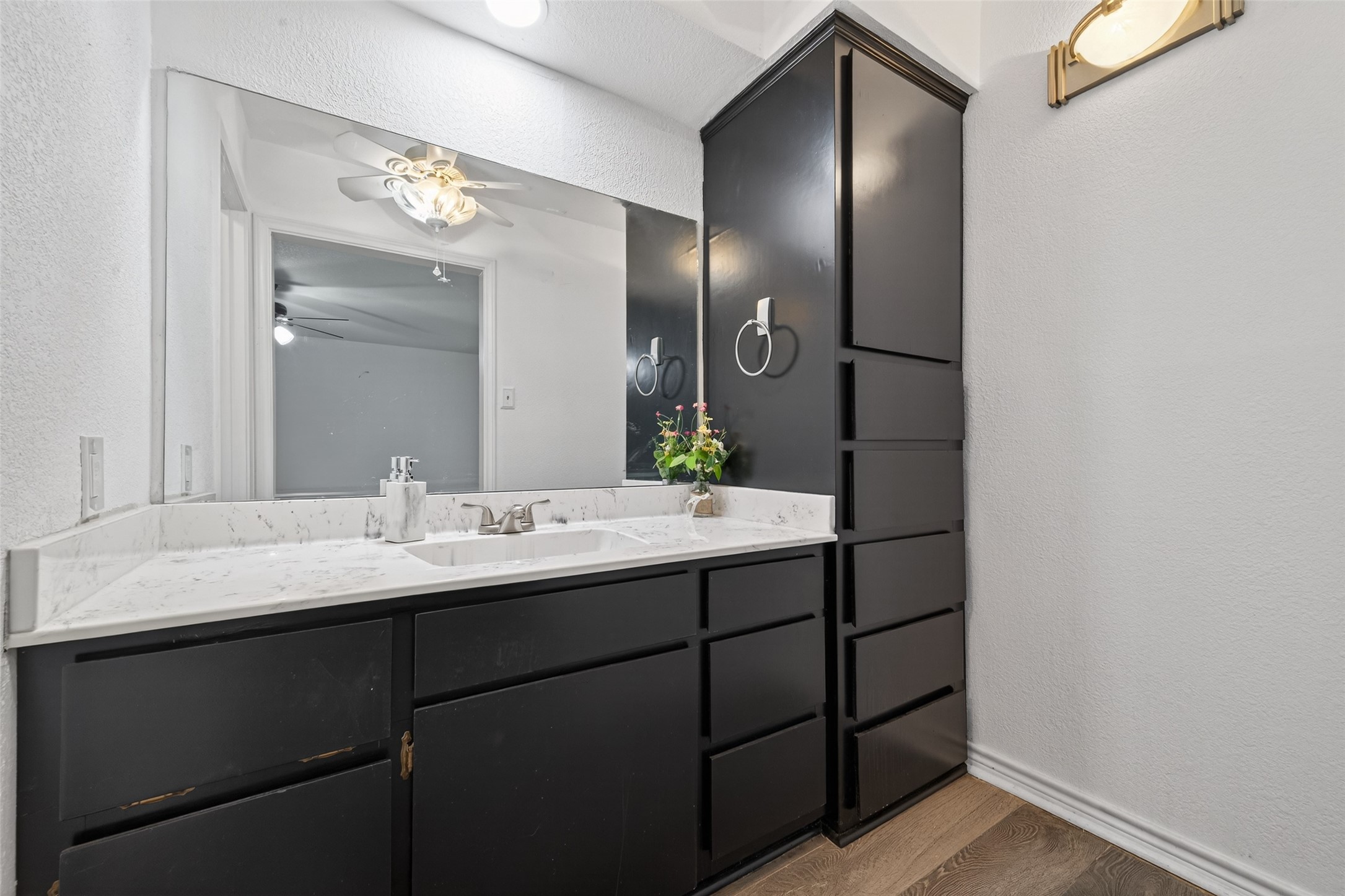 15335 Robin Trail Conroe, TX 77302 - Photo 20 of 38 Primary bathroom vanity area featuring sleek cabinetry, modern fixtures, and updated countertops. The space includes a ceiling fan for comfort, oversized mirror, and stylish lighting.