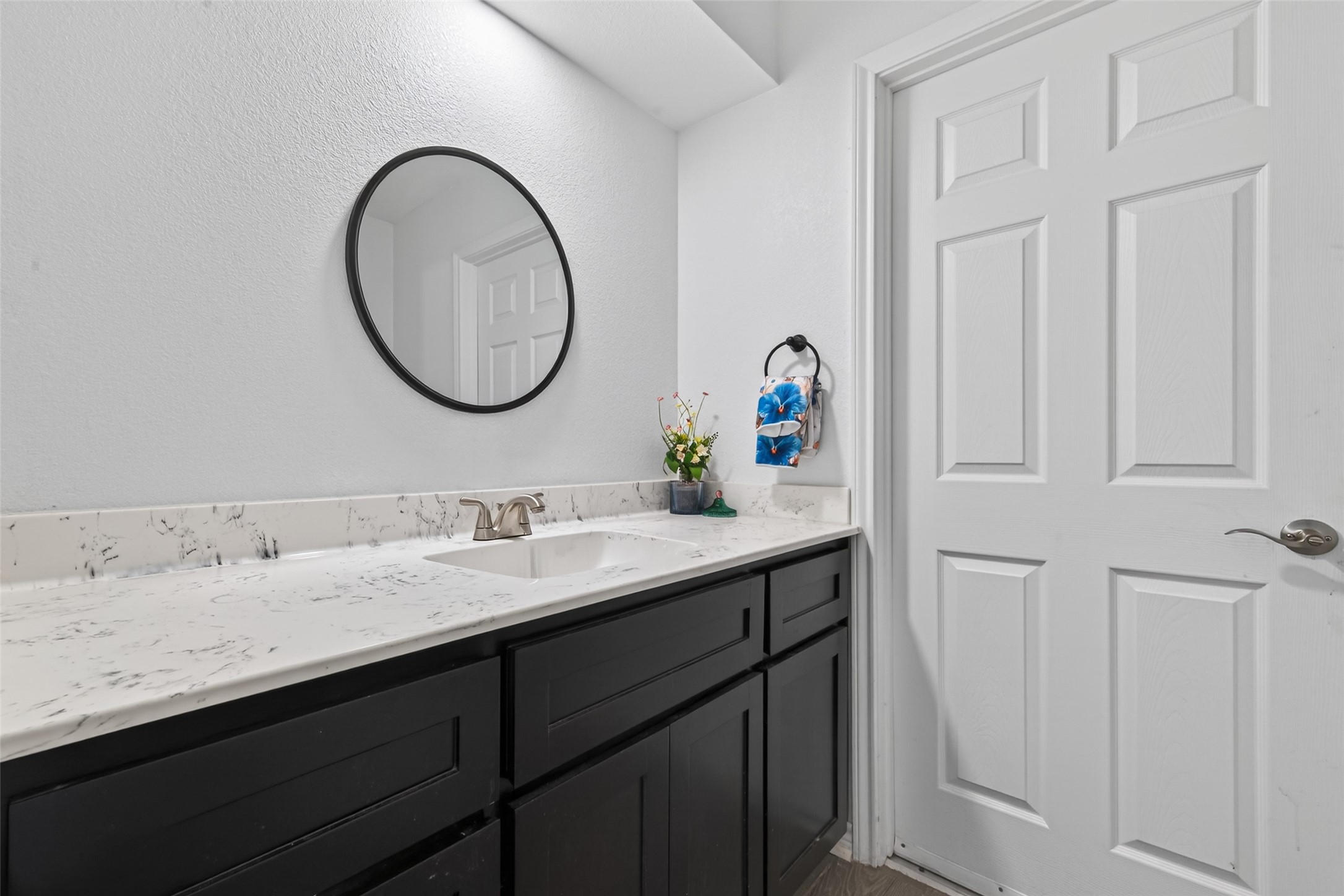 15335 Robin Trail Conroe, TX 77302 - Photo 35 of 38 Updated half bathroom featuring a modern vanity with sleek cabinetry, contemporary fixtures, and elegant white countertops. The well-appointed powder room includes a large mirror and durable wood-look flooring. This convenient en-suite half bath adds tremendous functionality to the adjacent flex room, making it ideal for multiple living needs.