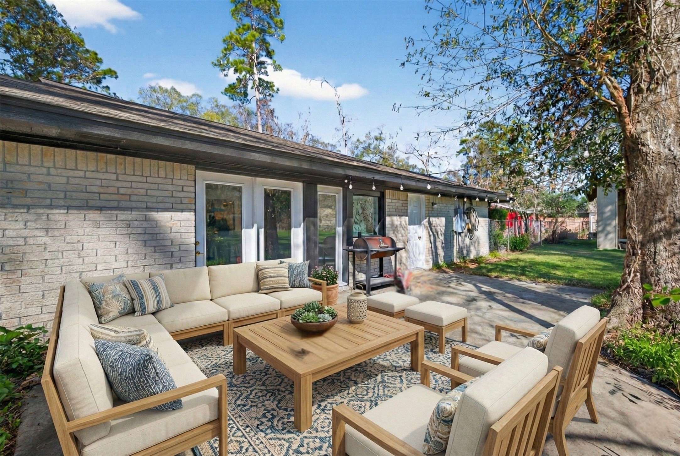 15335 Robin Trail Conroe, TX 77302 - Photo 36 of 38 Inviting virtually staged back patio with concrete flooring, perfect for year-round outdoor entertaining and relaxation. The spacious area provides ample room for dining and lounge furniture, with direct access from the living areas through French doors. Mature trees and a generous yard create a private, peaceful outdoor retreat ideal for gatherings or quiet evenings.