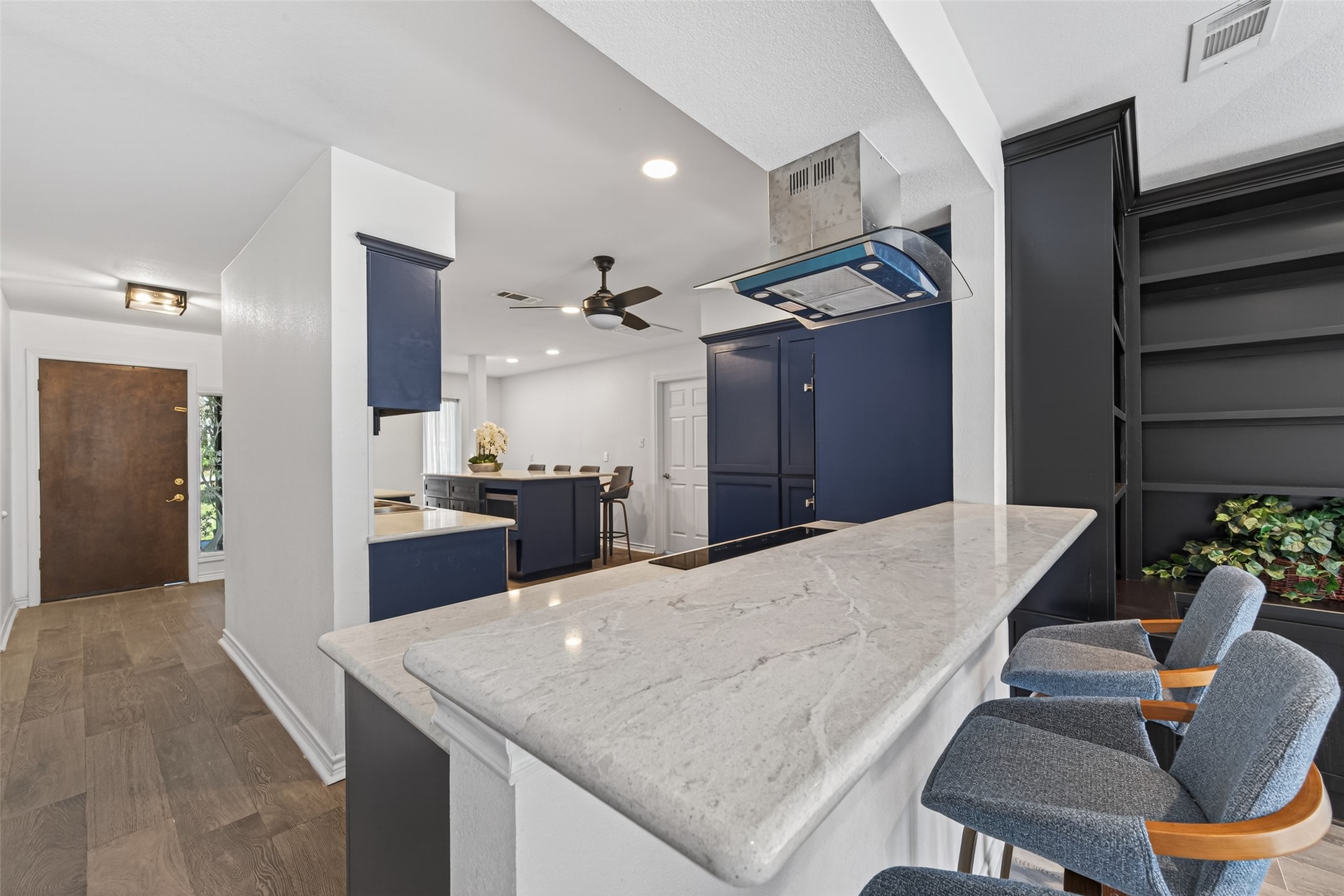 15335 Robin Trail Conroe, TX 77302 - Photo 10 of 38 Seamless open-concept design connecting the gourmet kitchen to living spaces, perfect for entertaining. The spacious layout features a large breakfast bar with contemporary seating and consistent wood-look tile flooring throughout. Multiple access points and excellent flow create an inviting atmosphere.