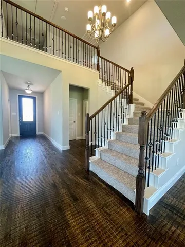 a view of staircase with railing and a chandelier