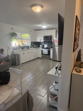 a large white kitchen with cabinets a sink a window and stainless steel appliances