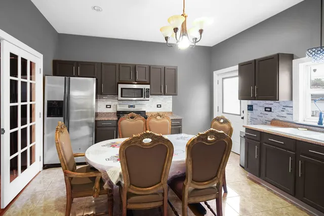 a kitchen with refrigerator a sink dishwasher a dining table and chairs with wooden floor