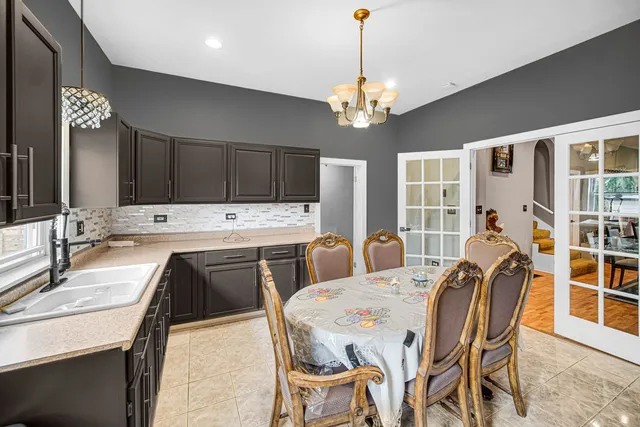 a view of a dining room with furniture a chandelier and kitchen view