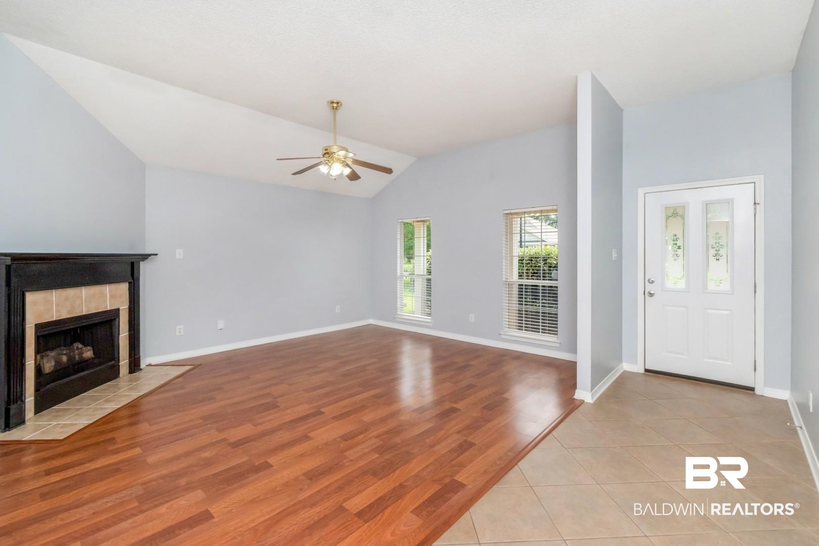2136 Spring Grove Court Mobile, AL 36695 - Photo 3 of 38 Spacious living area featuring a vaulted ceiling, wood-finish flooring, and a fireplace with a black mantel and tile surround