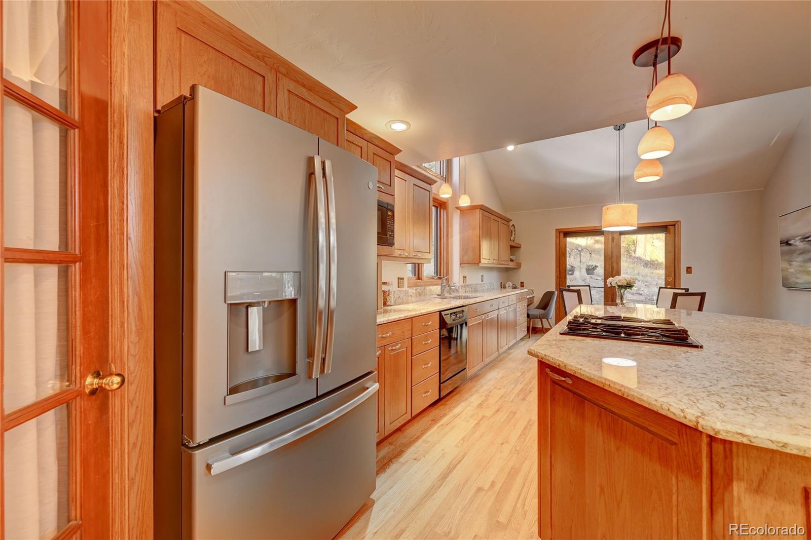 734 Spring Ranch Drive Golden, CO 80401 - Photo 16 of 40 a kitchen with stainless steel appliances granite countertop a refrigerator a stove and a sink with wooden floor