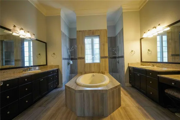 a spacious bathroom with a tub sink double vanity and a mirror