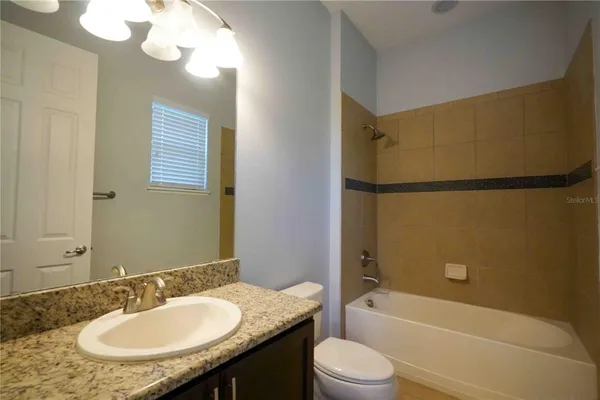 a bathroom with a granite countertop sink mirror toilet and bathtub