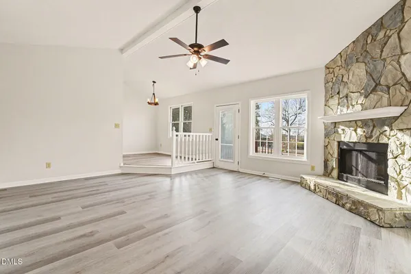 an empty room with windows and fireplace