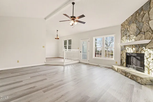 an empty room with windows and fireplace