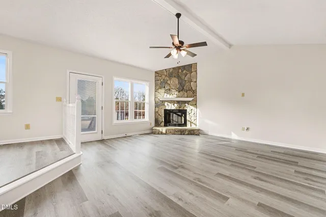 a view of empty room with a fireplace and wooden floor