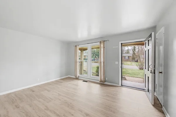 an empty room with wooden floor and windows