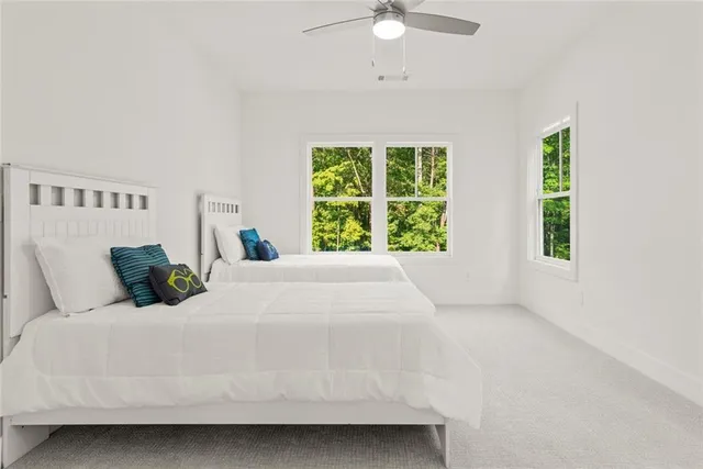 a bedroom with a bed couches and two windows