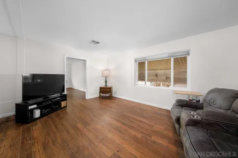 a living room with furniture and a flat screen tv with wooden floor