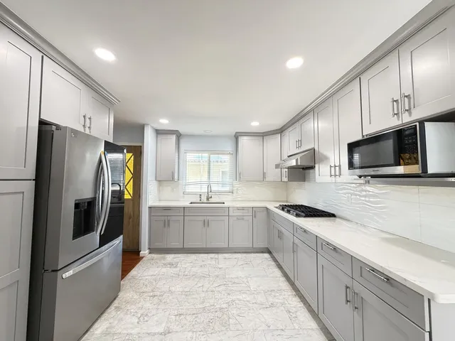 a large kitchen with cabinets stainless steel appliances and a counter space