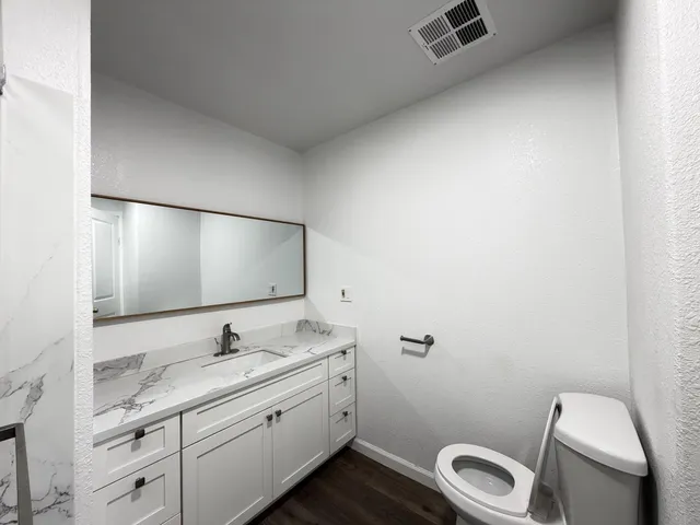 a bathroom with a granite countertop toilet sink and mirror