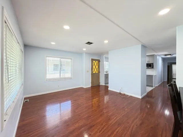 an empty room with wooden floor and windows