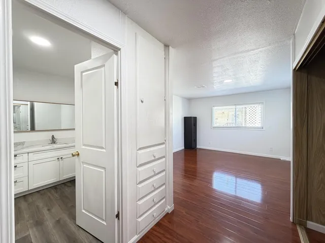 a view of a hallway with wooden floor and cabinet