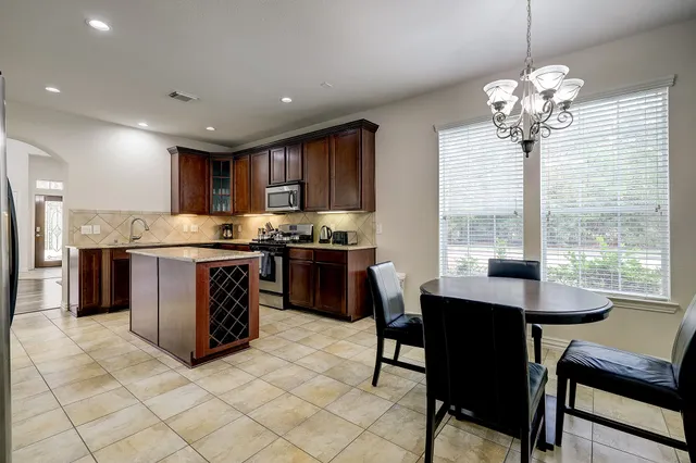 a kitchen with stainless steel appliances granite countertop a stove a refrigerator a sink dishwasher a dining table and chairs with wooden floor