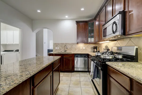 a kitchen with stainless steel appliances granite countertop a stove a sink and a microwave