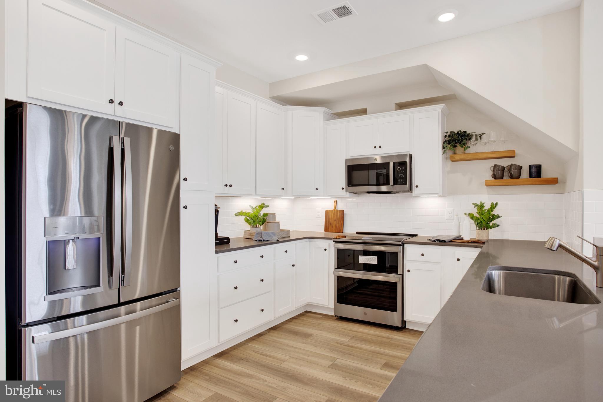 9664 Swallowtail Lane Manassas, VA 20110 - Photo 14 of 95 a kitchen with granite countertop a refrigerator a microwave a stove and white cabinets with wooden floor