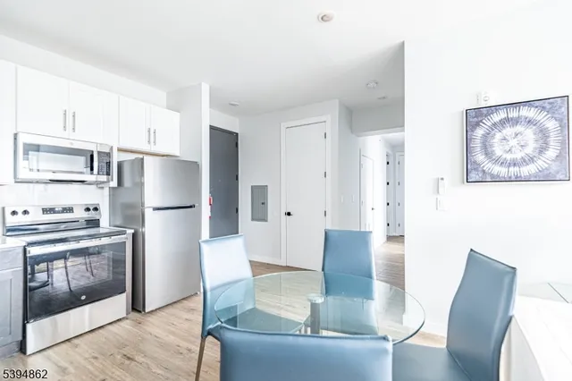 a kitchen with stainless steel appliances granite countertop a refrigerator a stove a dining table and chairs