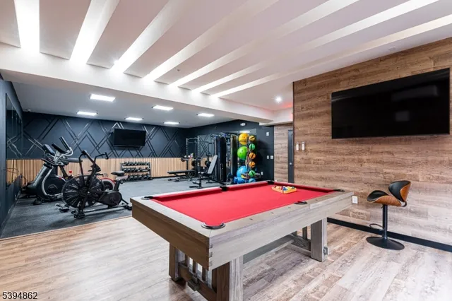 a room with furniture pool table flat screen tv and windows