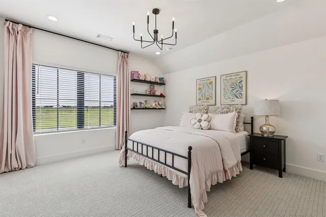 a spacious bedroom with a large bed and a chandelier