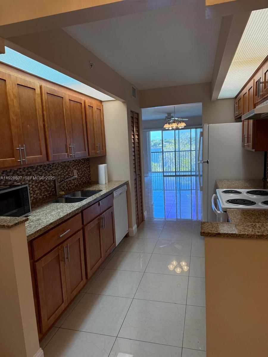 1201 Southwest 141st Avenue, Unit 304J Pembroke Pines, FL 33027 - Photo 10 of 31 a kitchen with stainless steel appliances granite countertop a sink counter space cabinets and a stove
