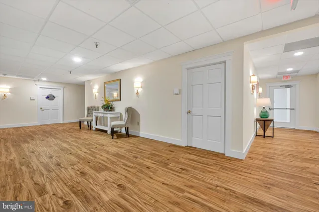 a view of an empty room with wooden floor and a kitchen