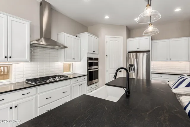 a kitchen with stainless steel appliances granite countertop a stove a refrigerator a sink dishwasher with a dining table and chairs with wooden floor