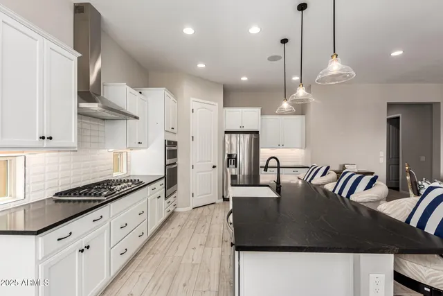 a kitchen with granite countertop a stove a sink a refrigerator a center island with wooden floor and cabinets