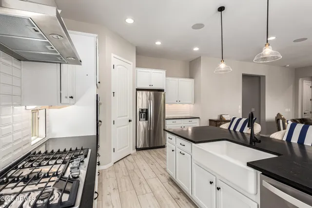 a kitchen with granite countertop a stove a sink a refrigerator and a wooden floor