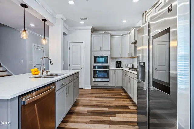 a view of kitchen with stainless steel appliances granite countertop a sink a stove and a wooden floors