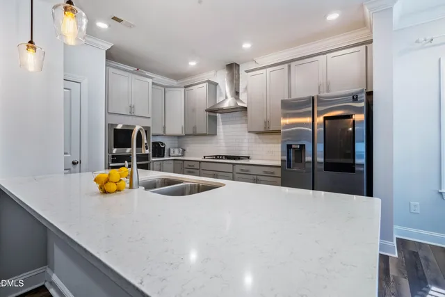 a kitchen with stainless steel appliances kitchen island granite countertop a refrigerator oven a sink and dishwasher with wooden floor