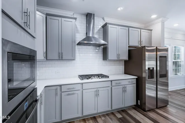 a kitchen with stainless steel appliances granite countertop a sink a refrigerator and a stove top oven