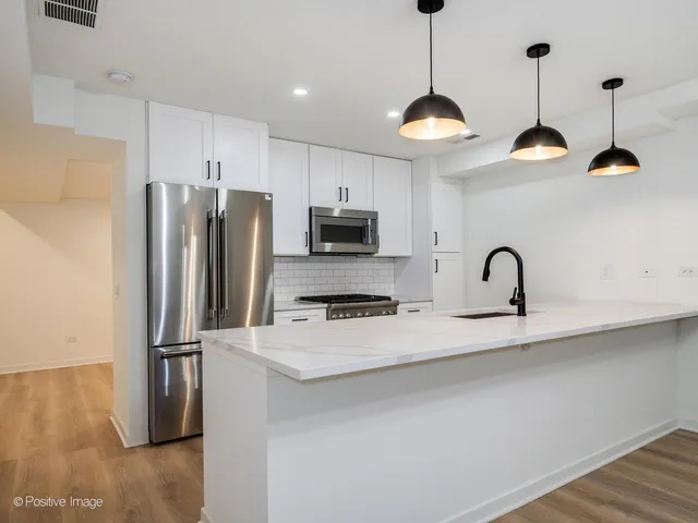 a kitchen with stainless steel appliances granite countertop a refrigerator a sink a stove a microwave a refrigerator and a stove